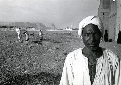 Objevitel fantastického pokladu Muhammad Ali Khalifah al-Samman stojí ve vesnici al-Qasr. V pozadí vpravo Deir Anba-Balamūn (klášter sv. Palamon) a Jabal al-Tarif je na levé straně.